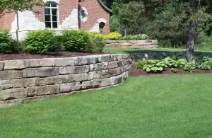 Retaining wall with landscaping and vibrant grass in a residential yard.