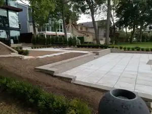 A concrete patio with a stone bench and a planter.