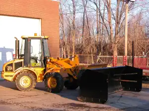 Tractor and attachment parked outside a building.