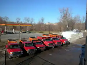 A row of salt trucks parked in a parking lot.