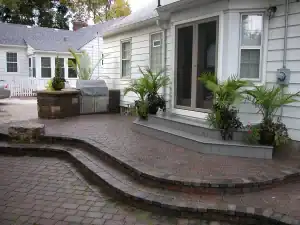 Red stone paved Patio with built-in barbeque and potted plants.