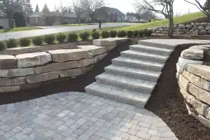 Gray block steps in between natural stone retaining walls.