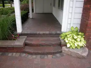 Outdoor brick pathway with landscaping and garden plants.