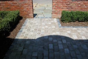 Cobblestone pathway with brick walls and greenery, outdoor landscaping by San Marino Services.