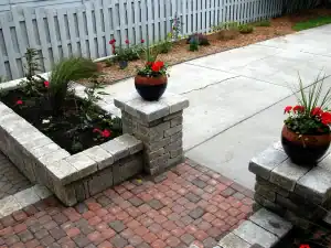 Outdoor garden with flower beds, potted plants, and brick walkway for landscaping.