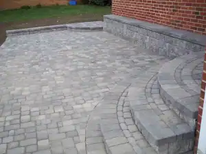 Outdoor stone patio with curved steps and retaining wall.