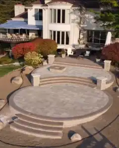Outdoor stone patio with steps, seating, and lush landscaping.