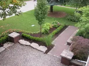 Outdoor garden landscaping with brick walkway and lush greenery.