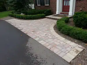 Beautifully paved front yard with brick pathway and lush green landscaping.