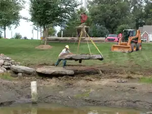 Outdoor stone pathway construction with heavy machinery and worker.