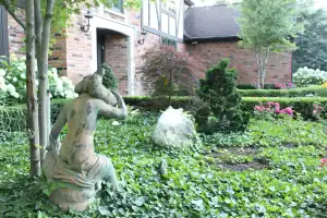 Serene garden featuring a classical stone statue surrounded by lush greenery and vibrant flowers.