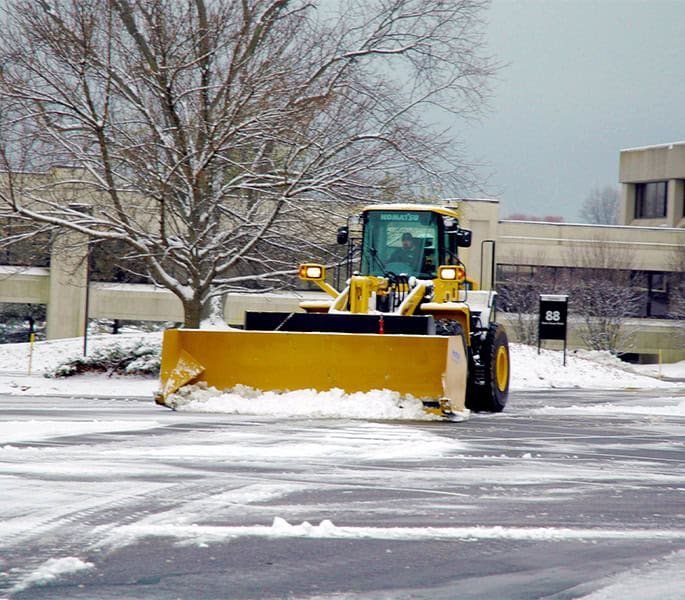 Snow removal equipment clearing a parking lot in winter.