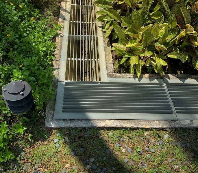 Drainage grates installed in a landscaped garden area for efficient water runoff.